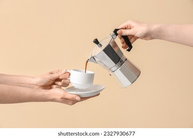 Woman pouring espresso from geyser coffee maker into cup on beige background - Shutterstock ID 2327930677