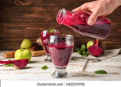 Woman pouring fresh beet smoothie into glass on table - Powered by Shutterstock