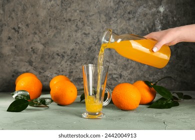 Woman pouring fresh orange juice from bottle into glass cup on grey background - Powered by Shutterstock