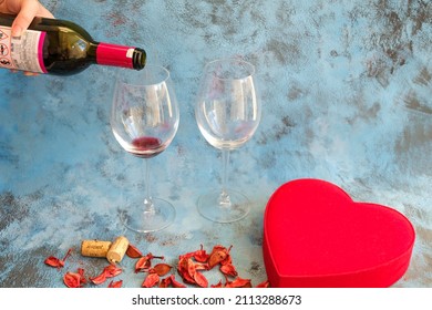 Woman Pouring Glass Of Red Wine From A Bottle. Preparation For A Special Valentine's Day Evening.