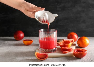 Woman pouring grapefruit juice from juicer into glass on grey background - Powered by Shutterstock