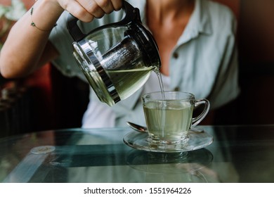 Woman Pouring Herbal Tea Into A Glass Cup