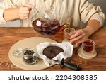 Woman pouring hot puer tea into cup at table