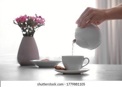 Woman pouring hot tea into cup at table, closeup - Powered by Shutterstock