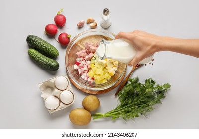 Woman Pouring Kefir Into Bowl With Ingredients For Okroshka On Grey Background