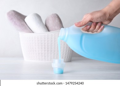 Woman pouring laundry detergent into cap on table against light background, closeup - Shutterstock ID 1479254240
