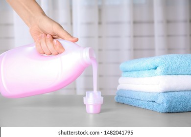 Woman pouring laundry detergent into cap on table against blurred background, closeup - Shutterstock ID 1482041795