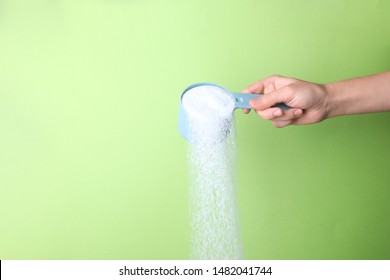 Woman pouring laundry detergent from measuring container against green background, closeup. Space for text - Shutterstock ID 1482041744