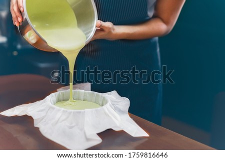 Woman pouring matcha green tea dough into a mold padded with parchment paper.