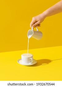 Woman pouring milk from a jug, in bright light, isolated on yellow-colored background. Milk dripping. Fresh organic morning drink. Milk over spilled. - Shutterstock ID 1932670544