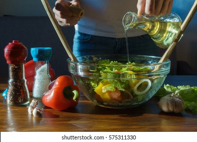 Woman Pouring Olive Oil Into Healthy Salad On Kitchen