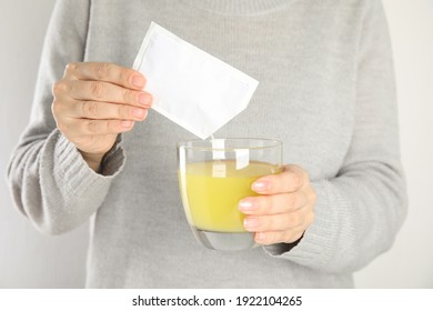 Woman Pouring Powder From Medicine Sachet Into Glass With Water, Closeup