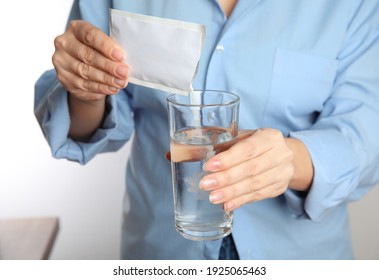 Woman pouring powder from medicine sachet into glass with water, closeup - Shutterstock ID 1925065463