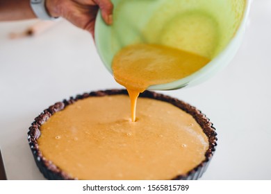 Woman Pouring Pumpkin Custard Into Pie Crust