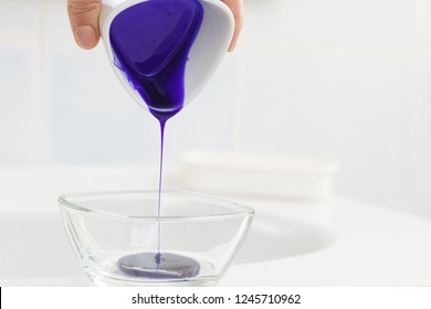 Woman Pouring Purple Hair Dye Or Shampoo Toner Into White Bowl. Hygiene Object Concept.