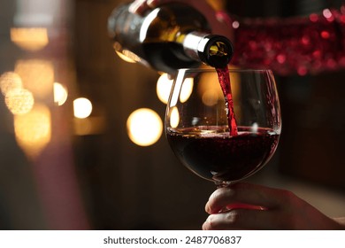 Woman pouring red wine from bottle into glass on blurred background, closeup. Space for text - Powered by Shutterstock