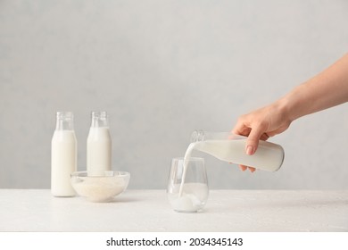 Woman pouring rice milk from bottle into glass on table - Shutterstock ID 2034345143
