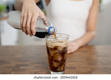 Woman pouring soda to glass for a refreshing drink