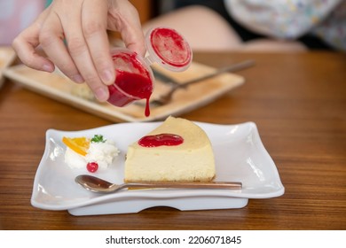 Woman Pouring Strawberry Sauce To Cheesecake. Sweet Dessert. Unhealthy Eating.