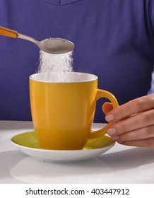 Woman Pouring Sugar On Coffee Cup.