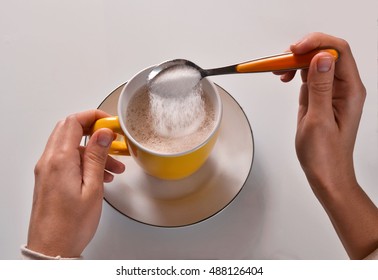 Woman Pouring Sugar On Coffee Cup With Teaspoon.