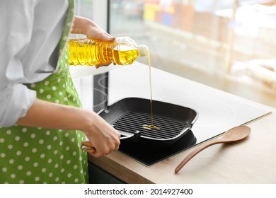 Woman Pouring Sunflower Oil Onto Frying Pan In Kitchen