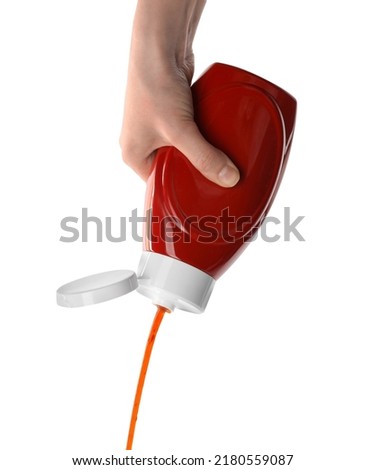 Woman pouring tasty ketchup from bottle on white background, closeup