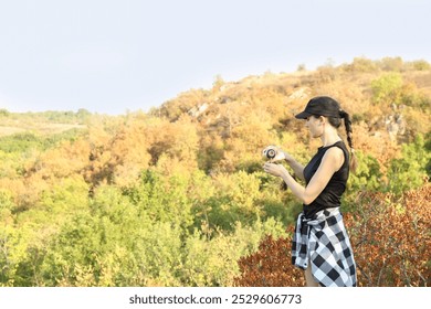 Woman pouring tea from thermos into cup near tree outdoors. Space for text - Powered by Shutterstock