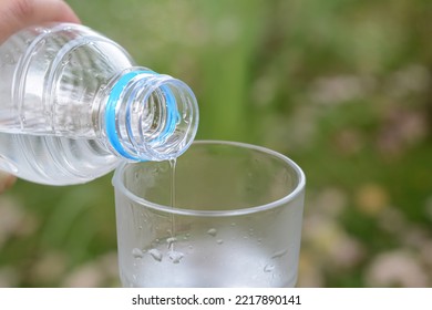 Woman Pouring Water From Bottle Into Glass Outdoors, Closeup