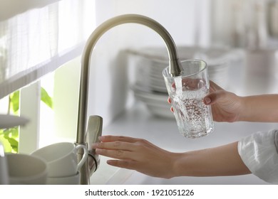 Mujer vertiendo agua en el vidrio en la cocina, en el armario