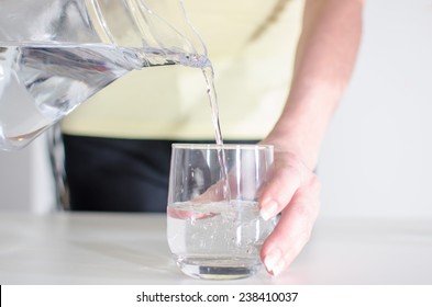 Woman Pouring Water From A Jug Into A Glass