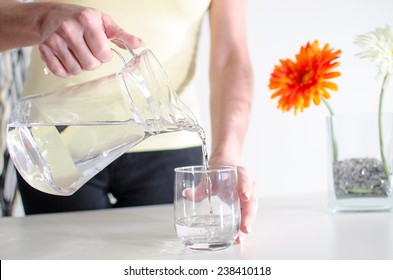 Woman Pouring Water From A Jug Into A Glass