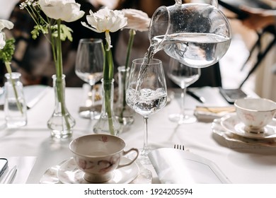 Woman pouring water from a transparent jug into a glass at a cafe. - Powered by Shutterstock