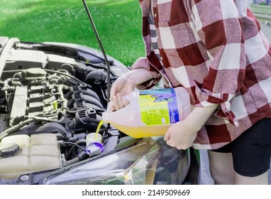 Woman Pouring Windshield Wiper Fluid Into 
Car Reservoir Container  