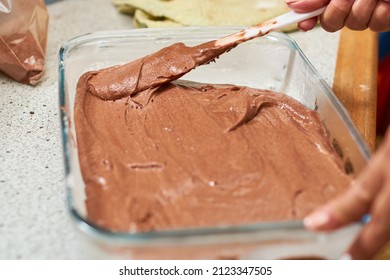 Woman Pours Brownie Batter Onto Glass Pan.