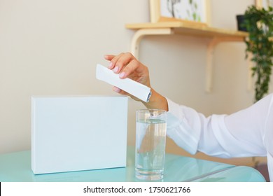 Woman pours the contents of a sachet into a glass. Universal stick pack for products of cosmetic and chemical industry. Possibility use for granulated, powder, viscous products. Mock up