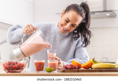 Woman pours fruit smoothie into cups in a kitchen. - Powered by Shutterstock