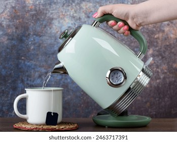 A woman pours hot water from a kettle into a cup with a disposable tea bag. - Powered by Shutterstock