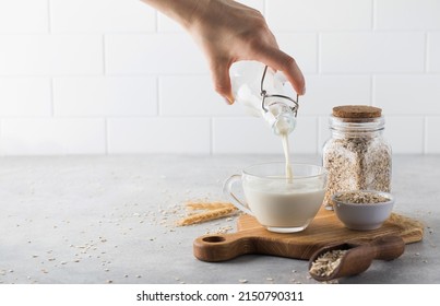 A Woman Pours Oat Milk Into A Mug. Alternative Milk. Copy Space.