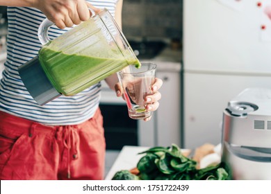 A woman pours a smoothie from a vitamin cocktail into a glass. Healthcare Cook at home. Lifestyle - Powered by Shutterstock