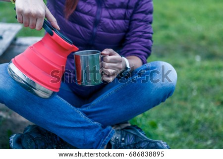 Woman pours tea from a kettle into the cup. Closeup concept