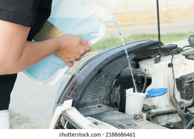 Woman Pours Windshield Cleaning Fluid. Flow Windshield Fluid Into The Windshield Washer Reservoir. Water Tank Wiper On Car Engine Room, Maintenance Concept.