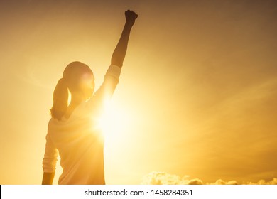 Woman power, victory and winning concept. Woman with fist in the air at sunset. 