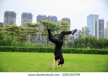Woman practice handstand on green spring lawn in park