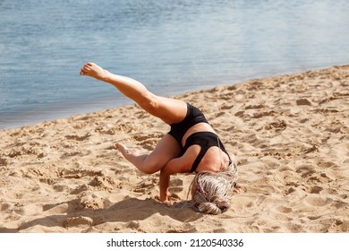 Woman Practice Yoga On The Beach In Summer, Doing Headstand And Handstand. Girl With Afro Hair Braids Exercising Outdoors Next To The River In Summer. 