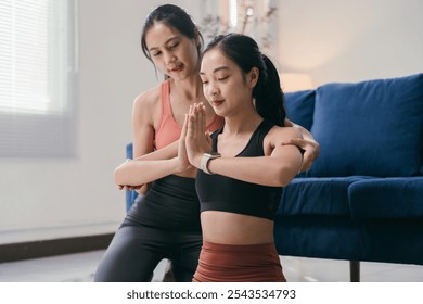 Woman practices yoga at home with her personal trainer, focusing on health and wellness in a serene setting - Powered by Shutterstock