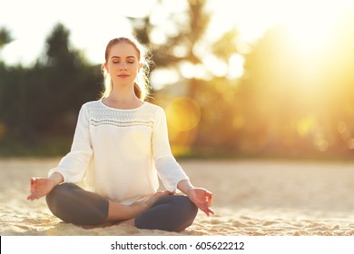 woman practices yoga and meditates in the lotus position on the beach
				