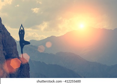 A woman practices yoga on a background of mountains and sky. Toned - Powered by Shutterstock