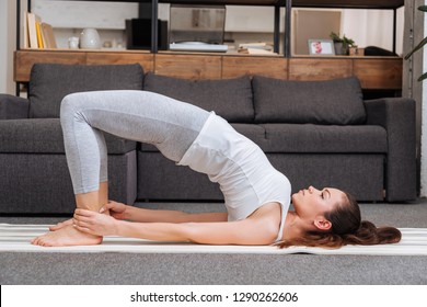 Woman Practicing Bridge Pose At Home In Living Room