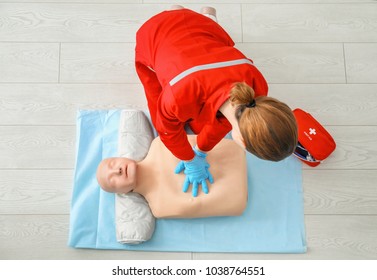 Woman Practicing CPR On Mannequin At First Aid Class